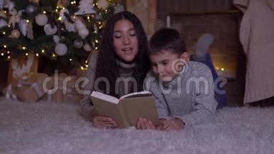 在圣诞节，妈妈给儿子读了一本书，吻了他躺在圣诞树附近的地板上。 <strong>高清高清</strong>